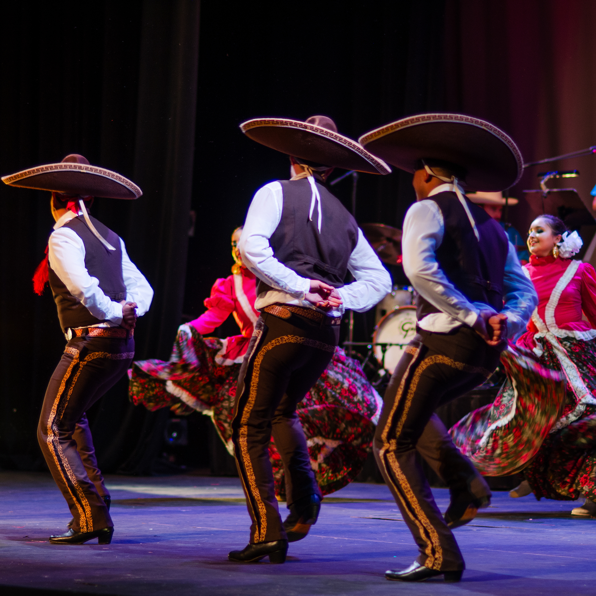 Three Mexican men dancing making their way to their partners